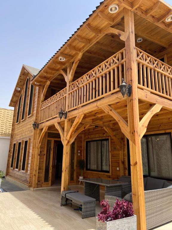 een groot houten huis met een groot terras bij أكواخ غيم ومطر in Al Hada