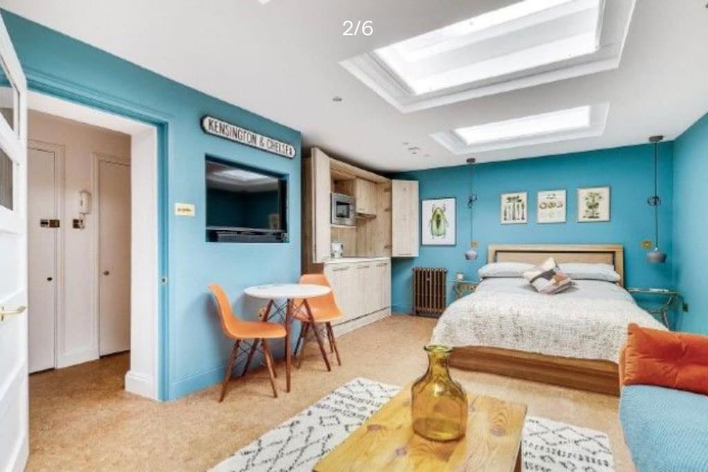 sypialnia z niebieskimi ścianami, łóżkiem i stołem w obiekcie Stylish Notting Hill Air Conditioned studio w Londynie