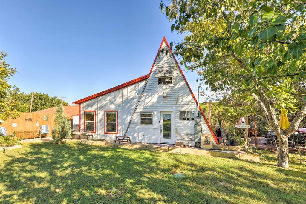 a white house with a red roof on a yard at Steps to Lake! Charming Cabin Pool Access and Decks in Granbury