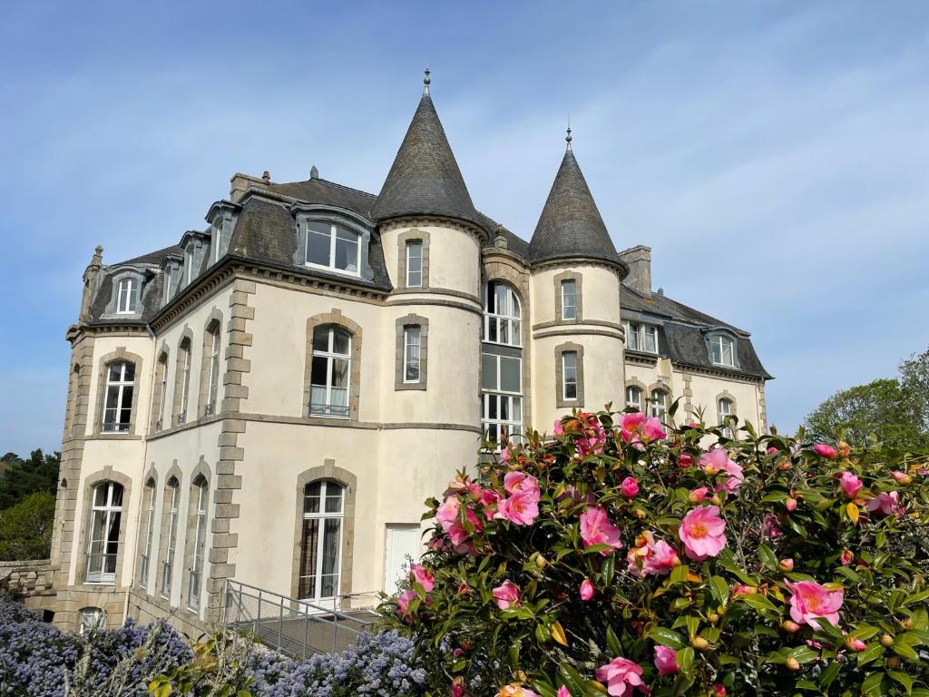ein altes Schloss mit rosa Rosen davor in der Unterkunft Un appartement au château de Locquéran Finistère in Plouhinec