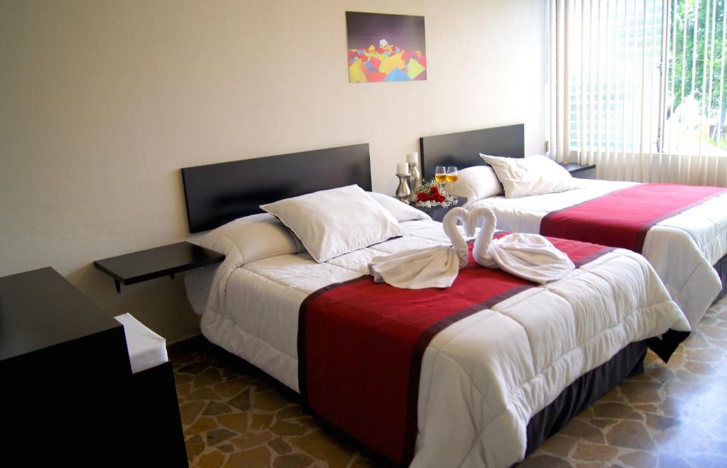 dos camas sentadas una al lado de la otra en una habitación en G y V Hotels, en Tegucigalpa
