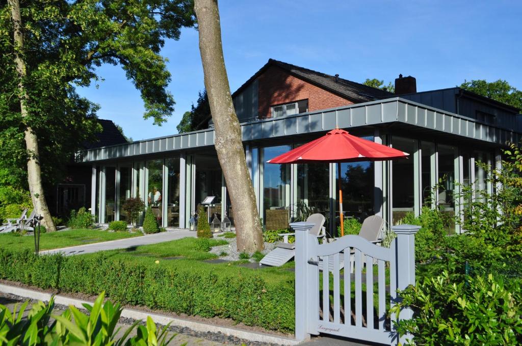 ein Haus mit einem weißen Zaun und einem Regenschirm in der Unterkunft Hotel Leegerpark in Greetsiel