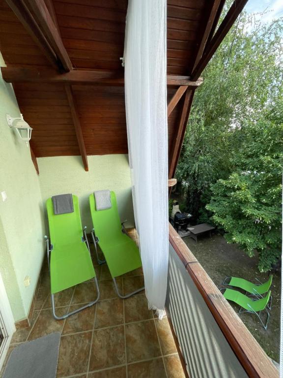 a balcony with green chairs and a white umbrella at Klebi’s apartmanház in Balatonföldvár
