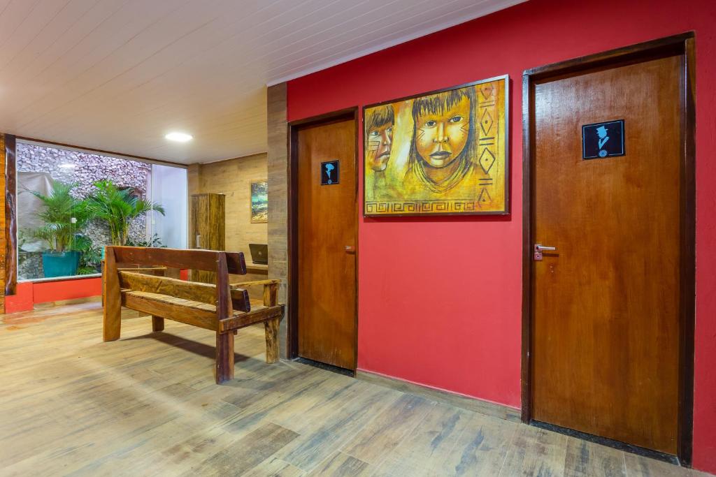 una habitación con una pared roja con un banco y una pintura en POUSADA SALOME en Bonito