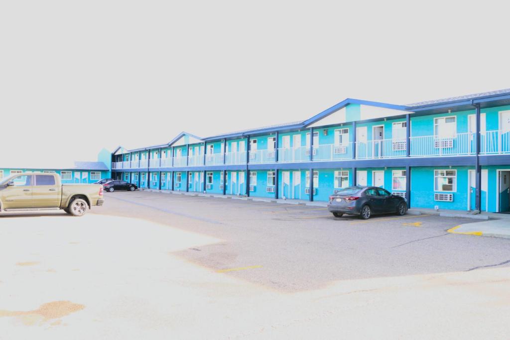 een blauw gebouw met auto's geparkeerd op een parkeerplaats bij Empire Inn & Suites in Red Deer