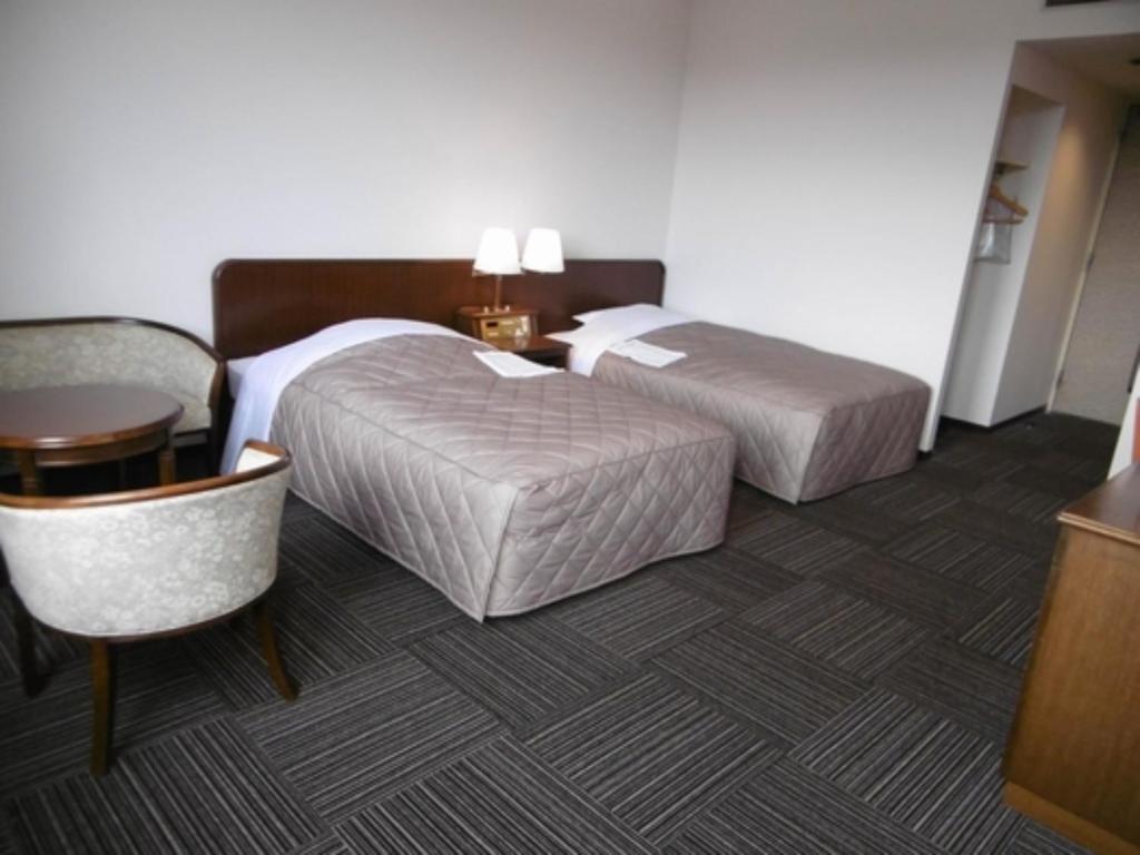 ein Hotelzimmer mit 2 Betten, einem Tisch und Stühlen in der Unterkunft Urban Hotel Nihonmatsu - Vacation STAY 78339v in Nihommatsu