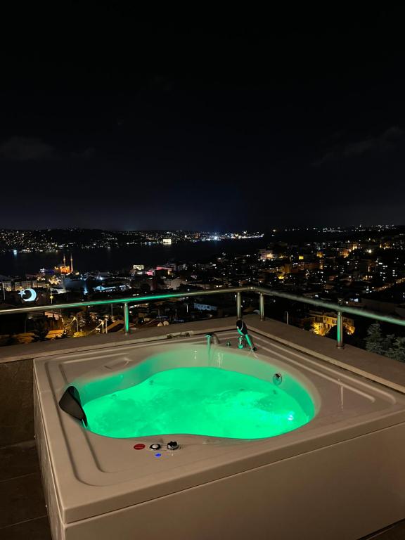 Class Hotel Bosphorus With Jacuzzi في إسطنبول: حوض استحمام ساخن على سطح مبنى في الليل