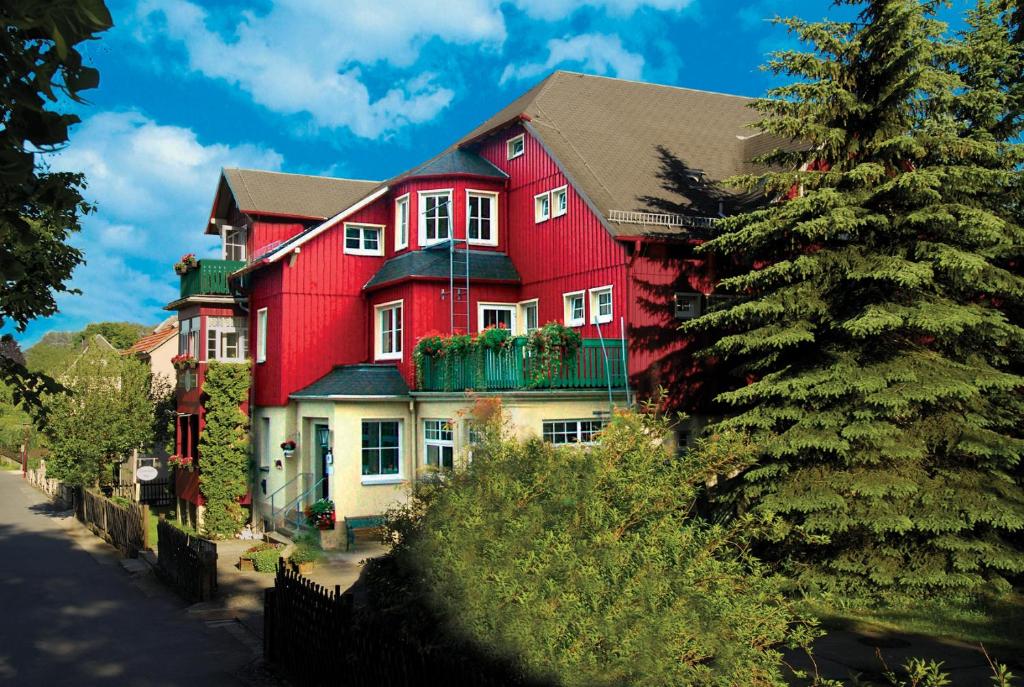 una gran casa roja con un árbol delante en Pension Villa Irene en Kurort Gohrisch