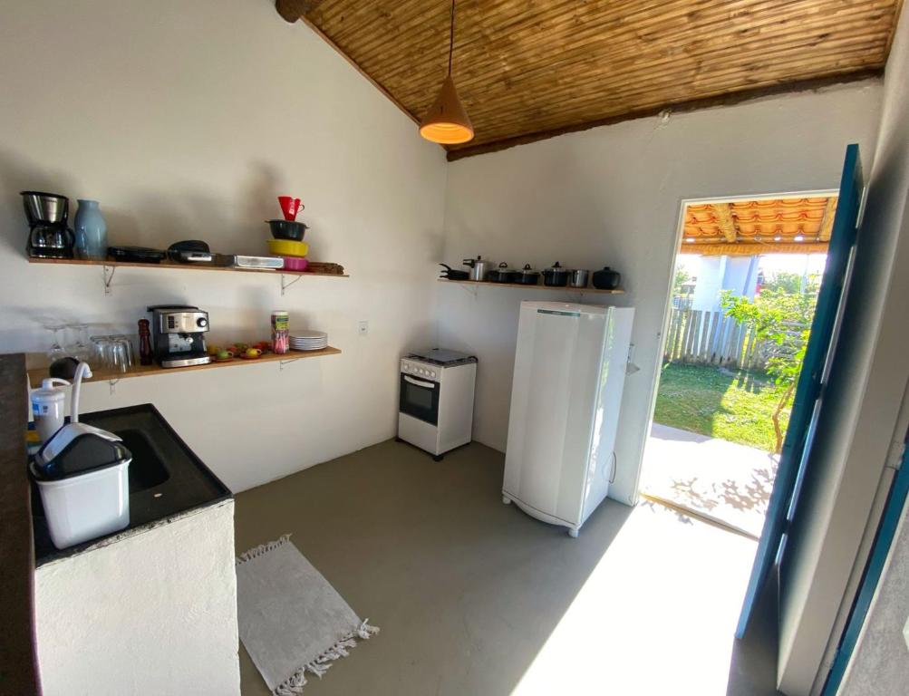 a kitchen with a white refrigerator and a window at OCA Caraíva in Caraíva