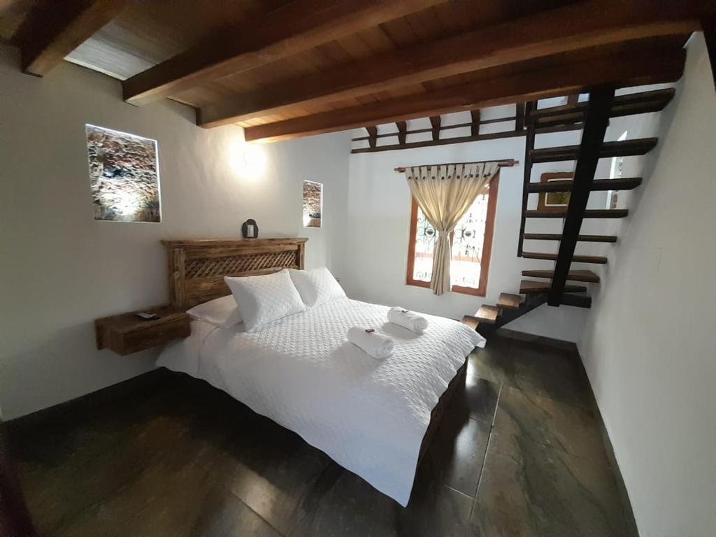 a bedroom with a white bed with two teddy bears on it at Hostal La Casita de Toñito in Villa de Leyva