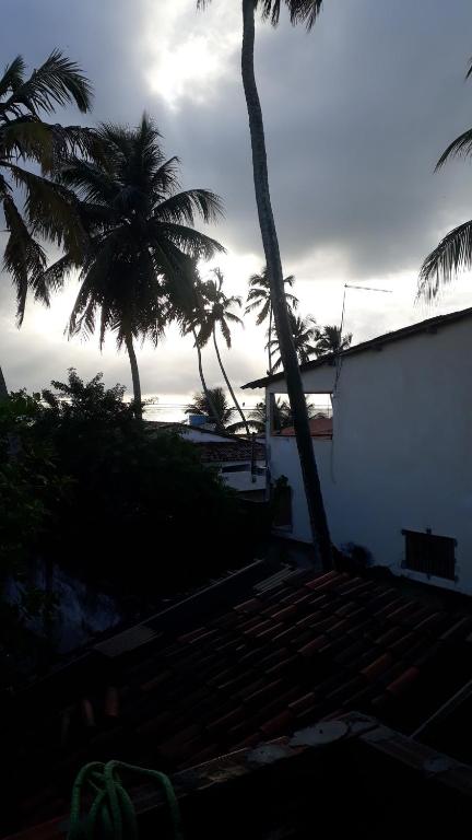 ein Gebäude mit Palmen im Hintergrund mit dem Meer in der Unterkunft Recanto do Sossego Tavares in Baía da Traição