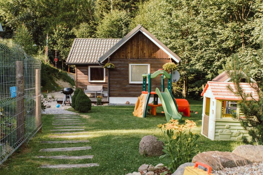 a small house with a playground and a slide at Chata na odludziu - góry, las, widoki, cisza i spokój in Jaszczurowa