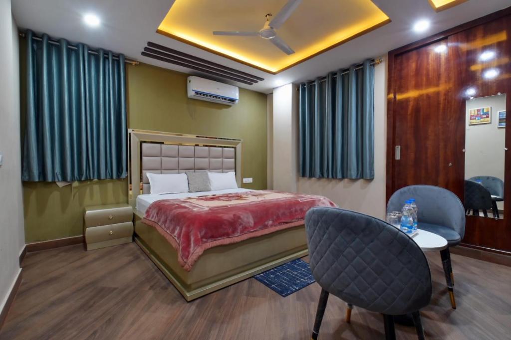 a bedroom with a bed and two chairs and a table at Hotel Lilac Doors in Patna