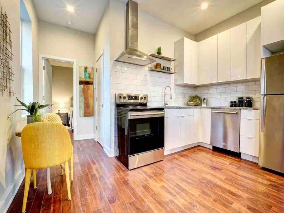 a kitchen with white cabinets and a wooden floor at CUTE & COZY/TQL stadium/ Findlay Market/Brewery in Cincinnati