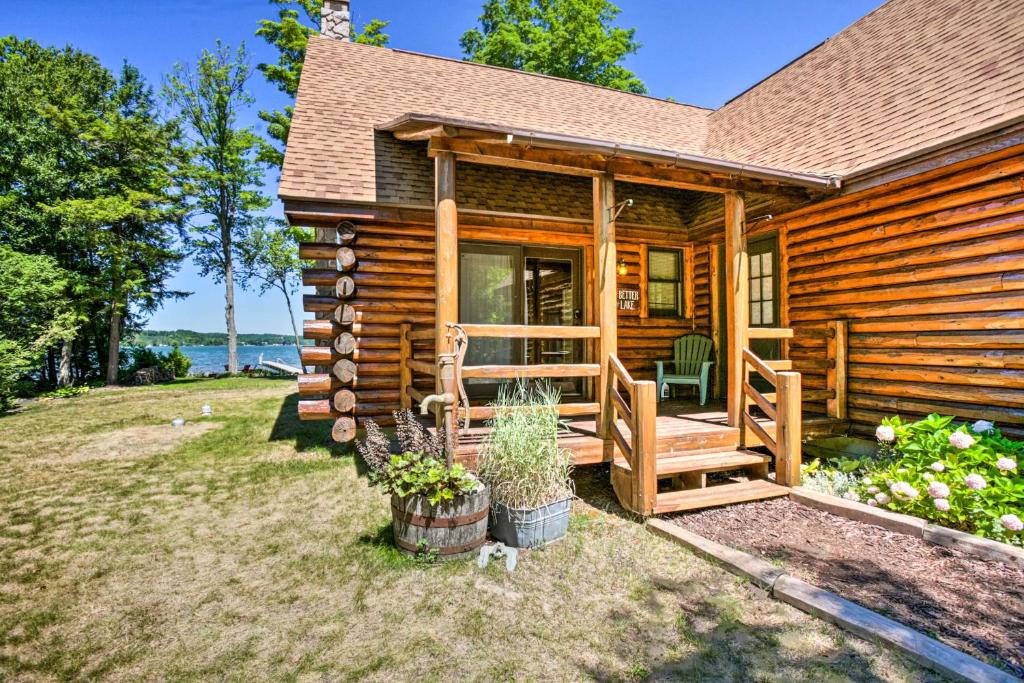 a log cabin with a porch and a patio at Waterfront Lake Leelanau Log Cabin with Private Dock in Lake Leelanau