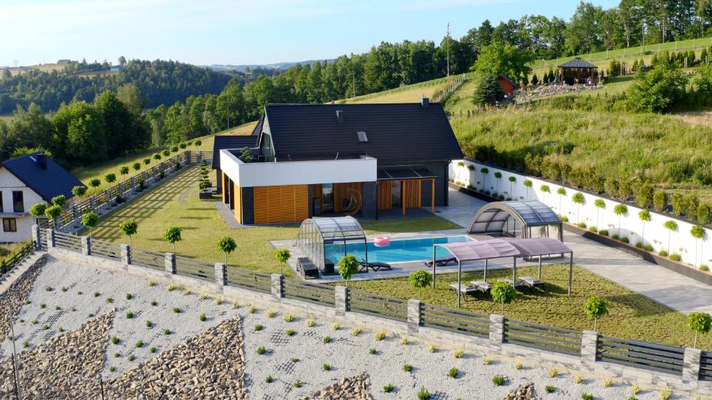 uma vista aérea de uma casa numa colina com uma piscina em BLACK ROCKS domki na wynajem em Nowy Sącz
