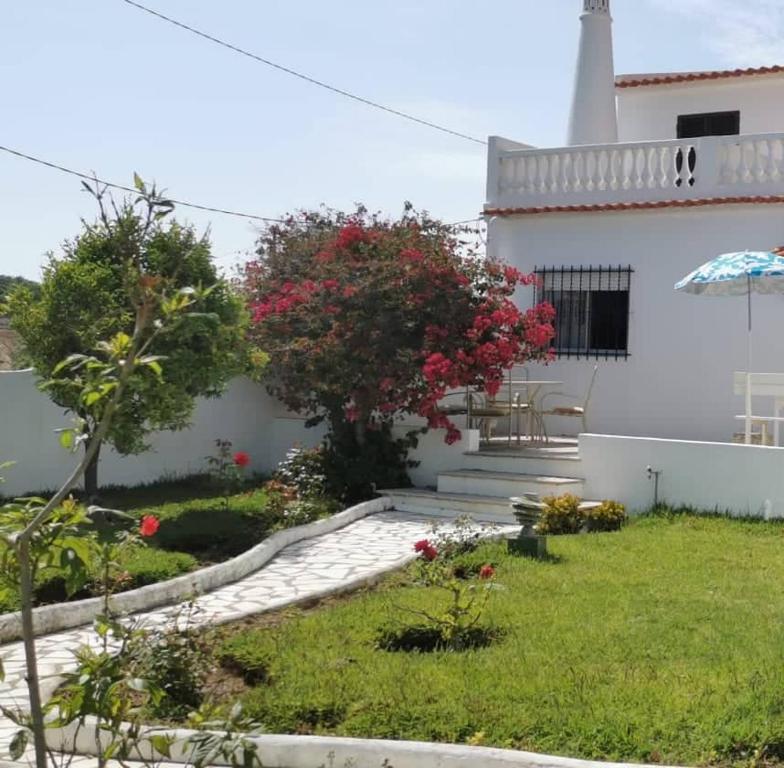 um jardim em frente a uma casa branca em Vivenda Miraflores em Armação de Pêra
