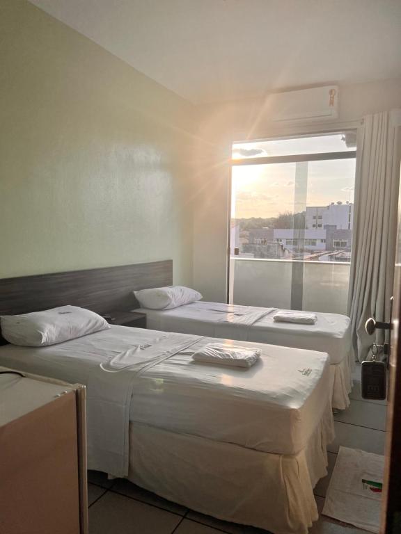dwa łóżka w pokoju z oknem w obiekcie Hotel Pinheiro w mieście Ibiapina