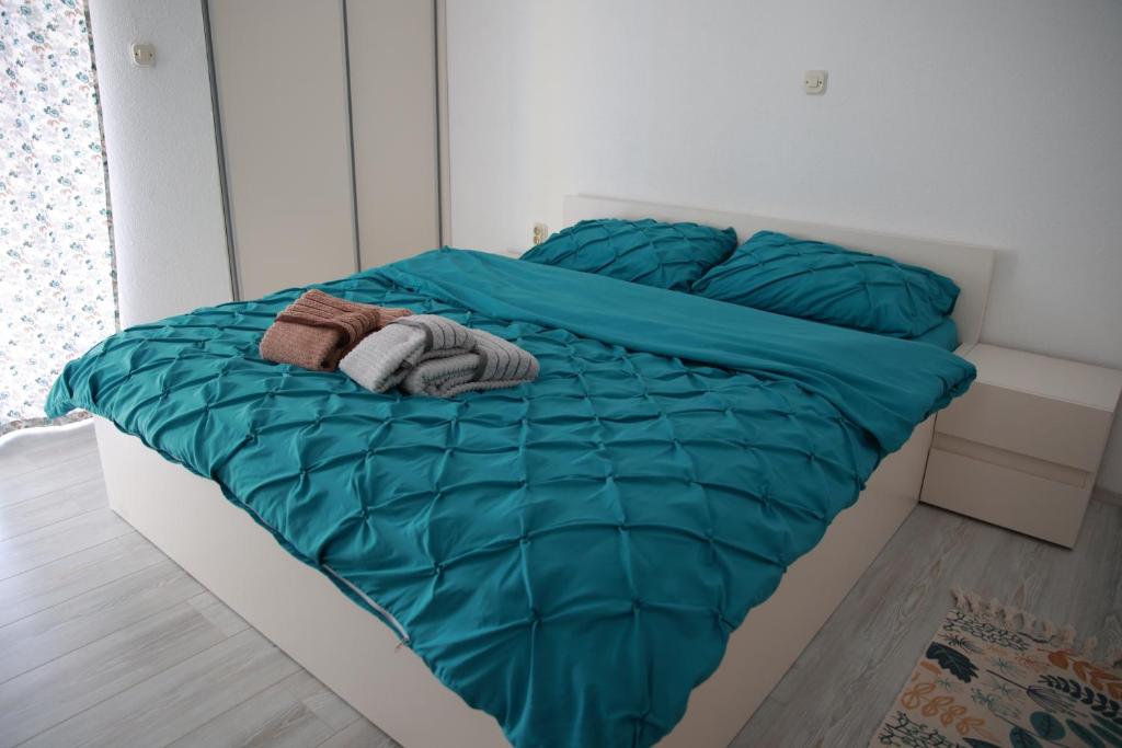 a bed with a green comforter and two towels at Cavleski apartment in Prilep