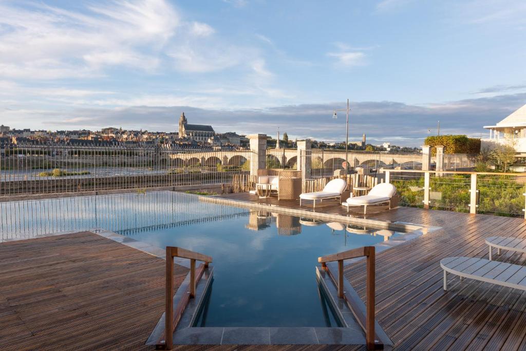 uma piscina com duas cadeiras e um deque de madeira em Fleur de Loire em Blois