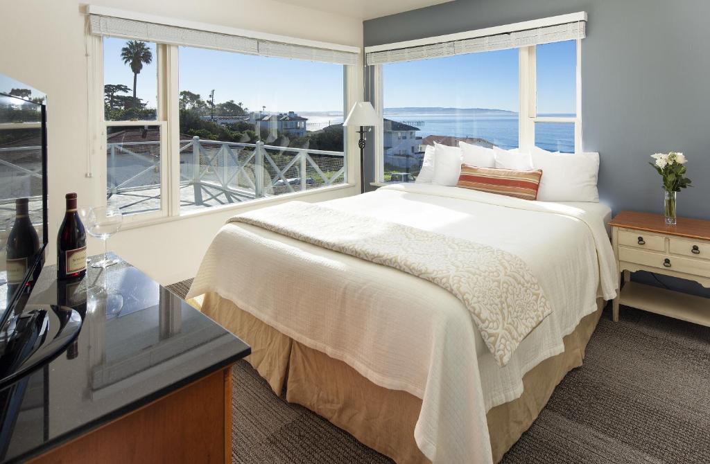 sypialnia z dużym łóżkiem i dużym oknem w obiekcie Tides Oceanview Inn and Cottages w mieście Pismo Beach