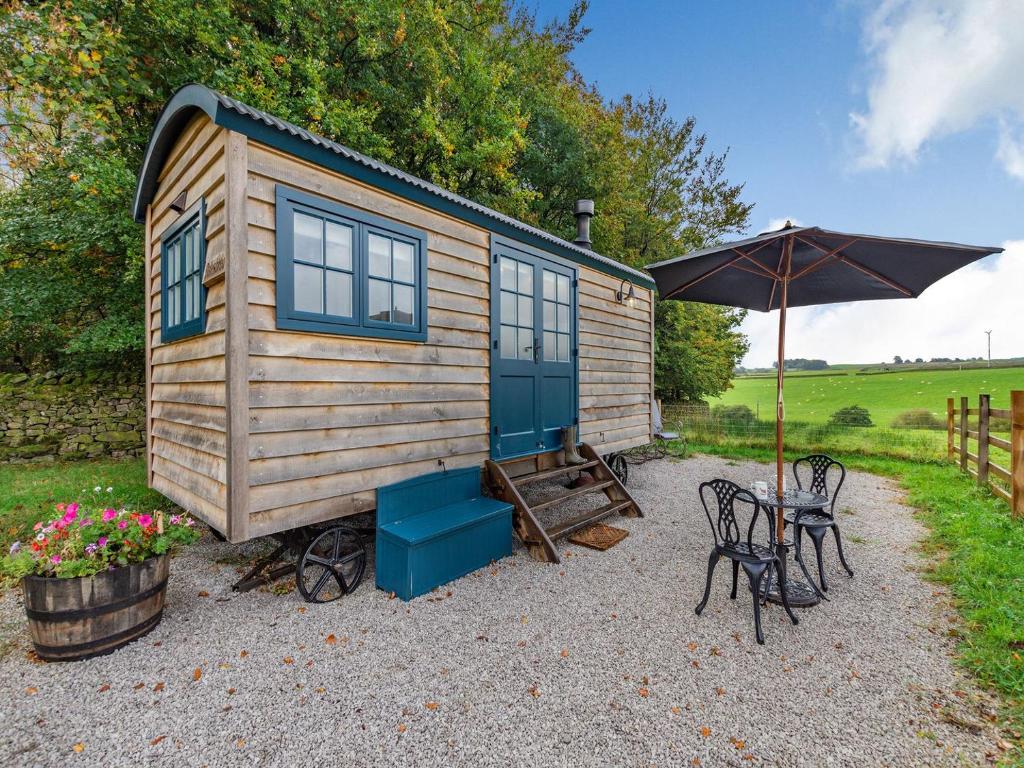 een tiny house met een tafel en stoelen en een paraplu bij The Dalesbred Hut - Uk40150 in Rathmell