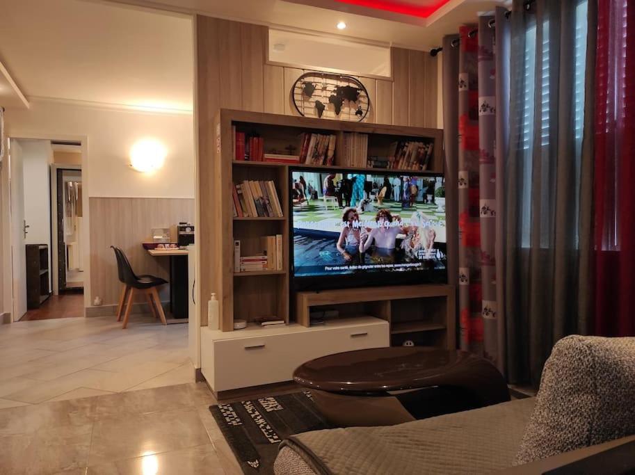 a living room with a flat screen tv in a entertainment center at Logement entier agréable et accueillant in Vaulx-en-Velin