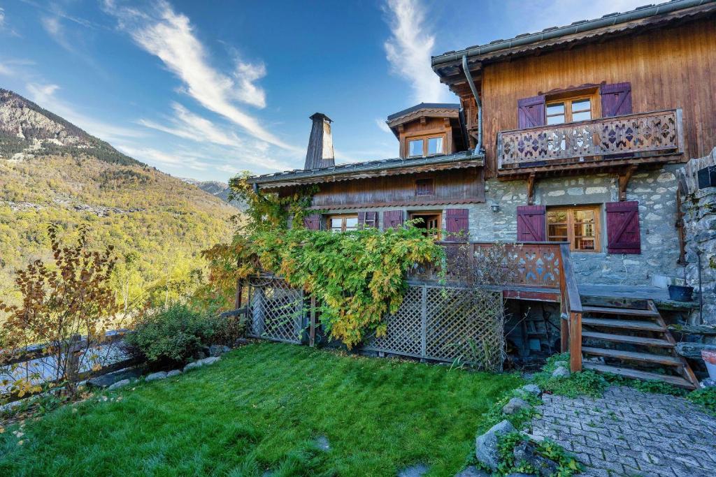 uma casa antiga com uma varanda e um quintal em Magnifique chalet authentique au cœur des 3 vallées em Courchevel