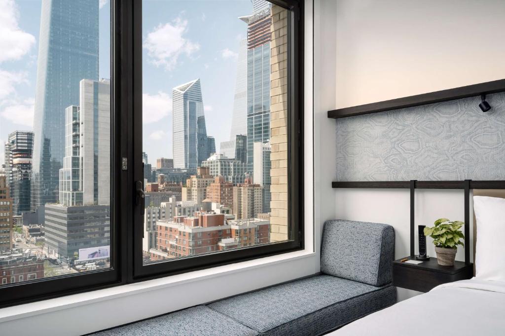 a bedroom with a view of the city from a window at Arlo Midtown in New York