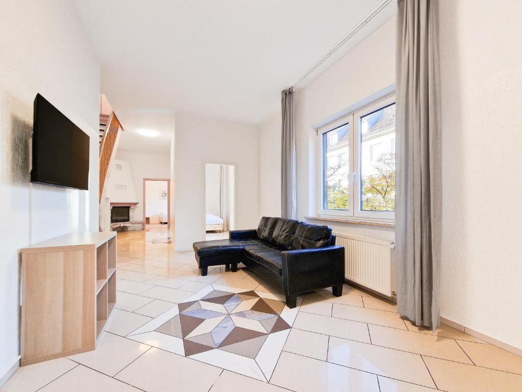 een woonkamer met een zwarte bank en een televisie bij RAJ Living - 2 , 3 and 4 Room Apartments - 25 Min Messe DUS in Duisburg