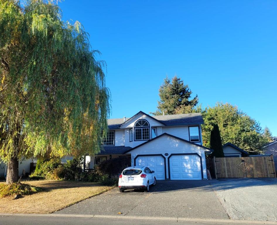 un coche blanco estacionado frente a una casa en Valleyview, en Courtenay