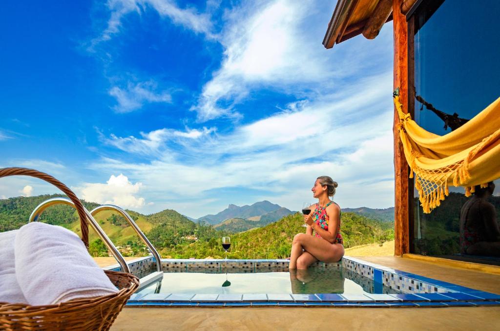 una mujer sentada en una piscina en un resort en Pousada Lua de Minas, en Visconde De Maua