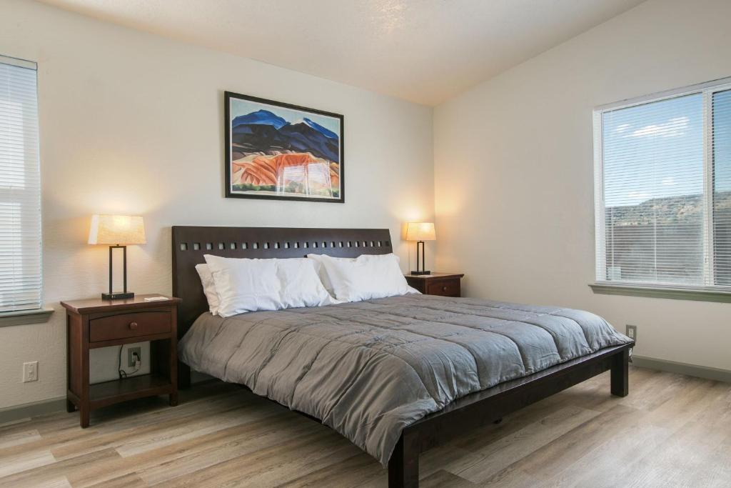 a bedroom with a bed with two night stands and two windows at Casa Chiliwood in Albuquerque