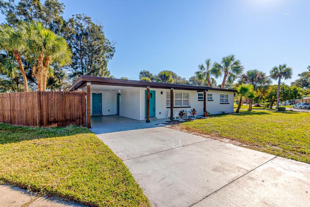 a small white house with a fence and palm trees at Suwannee Lane in Cocoa Beach