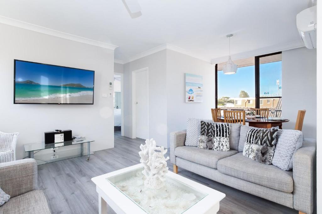 a living room with a couch and a table at Bellevue, 7 4 Donald Street - renovated unit with air con and Wi-Fi with views & central to CBD in Nelson Bay