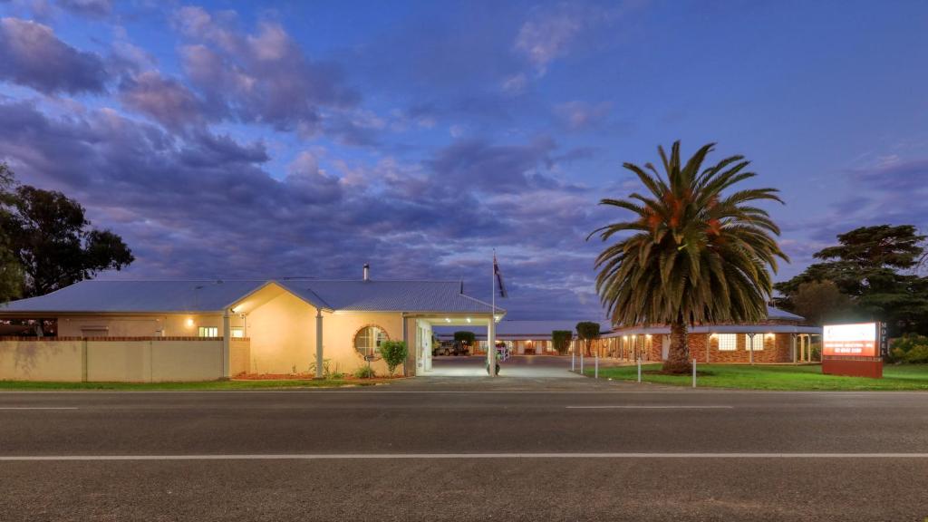 a house with a palm tree in front of a street at Country Gardens Motor Inn in Cowra