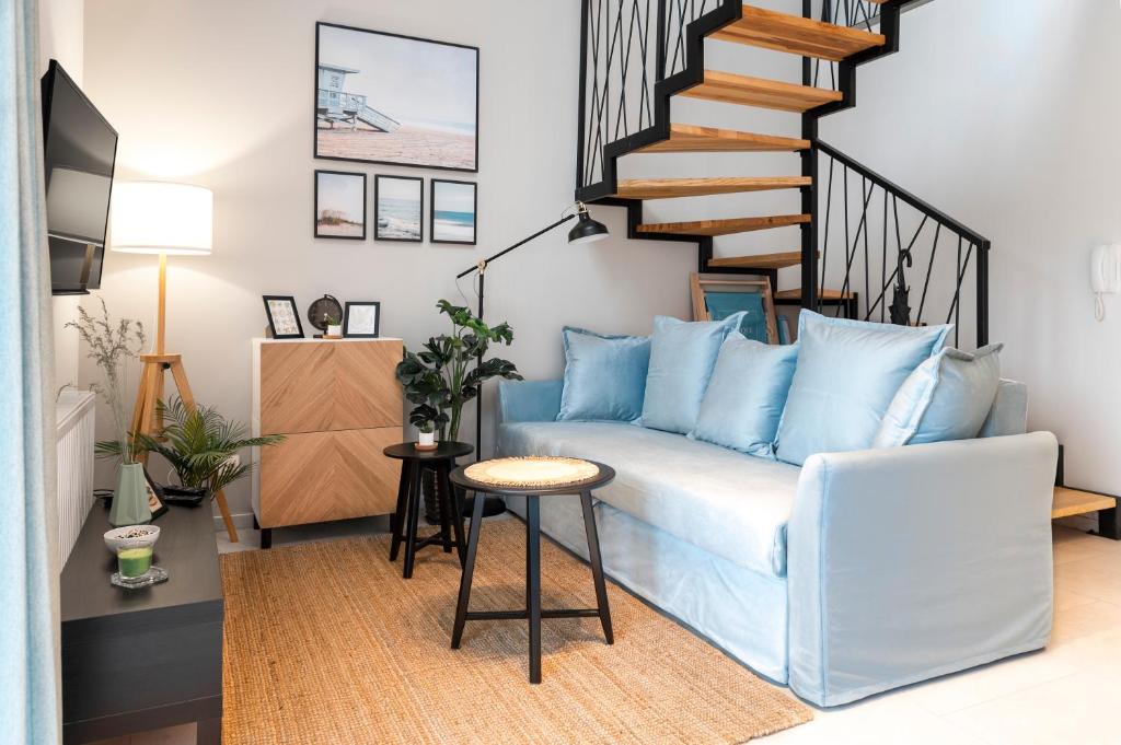 a living room with a blue couch and a staircase at Baltique Apartment in Niechorze