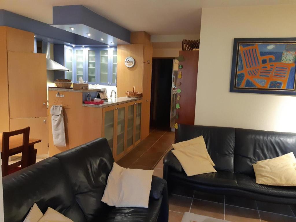 a living room with a black leather couch and a kitchen at Appartement Courchevel 1550, 3 pièces, 6 personnes - FR-1-514-74 in Courchevel