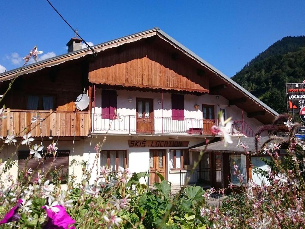 une maison dans les montagnes avec des fleurs au premier plan dans l'établissement Appartement cosy 6 pers. avec balcon au village, proche parking et local à skis - FR-1-342-291, à Beaufort
