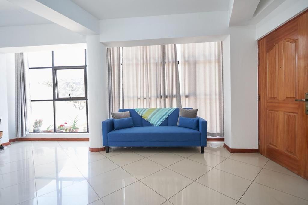 a blue couch in a living room with two windows at A 3 Cdras del Centro histórico, Amplio y en Piso 2 in Trujillo