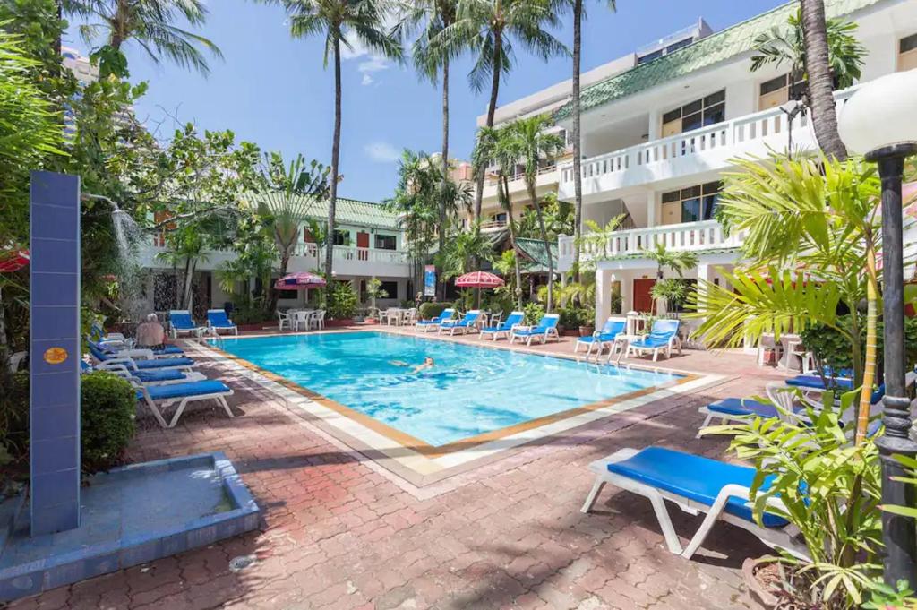 a pool in front of a hotel with chairs and a building at The Expat Hotel in Patong Beach