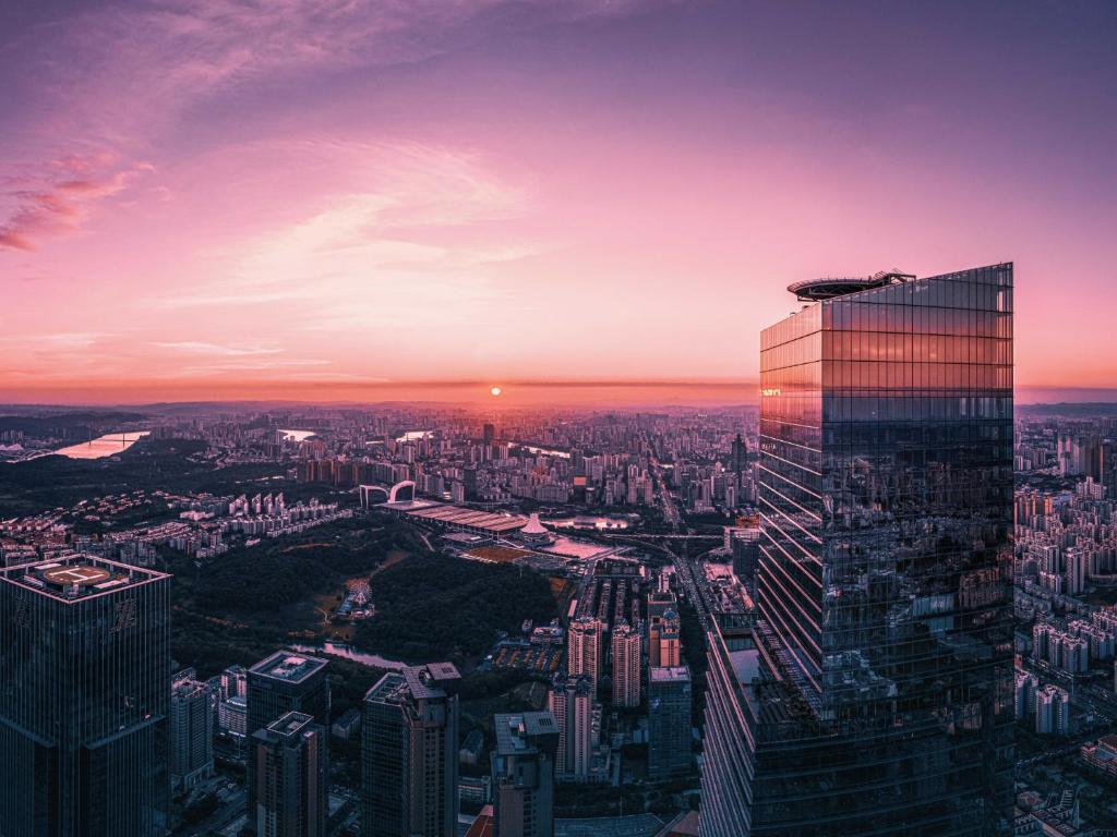 une vue sur les toits de la ville au coucher du soleil avec un grand bâtiment dans l'établissement Shangri-La Nanning - The tallest hotel worldwide in Shangri-La Group, à Nanning