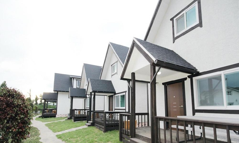 una fila de casas blancas con techos negros en Zain Village, en Seogwipo