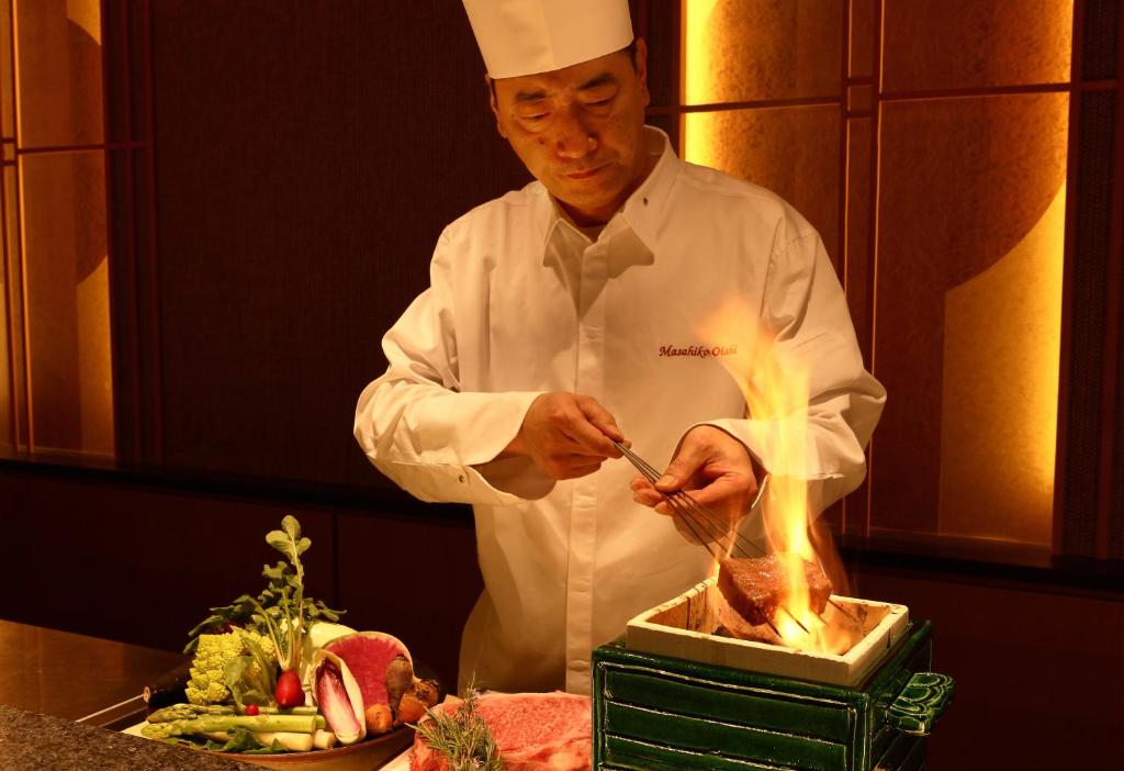 un chef cocinando comida a la parrilla en una cocina en Yado Shiontei en Yonago