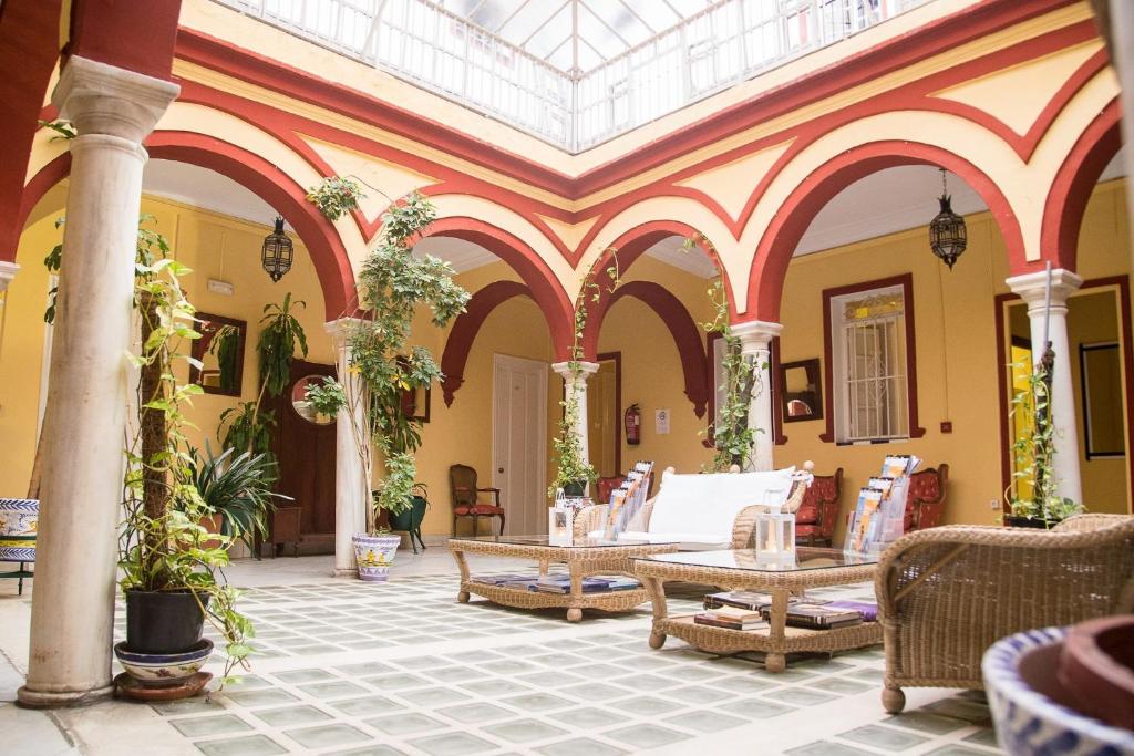 un hall avec des chaises et des tables dans un bâtiment dans l'établissement Hostal Sierpes, à Séville