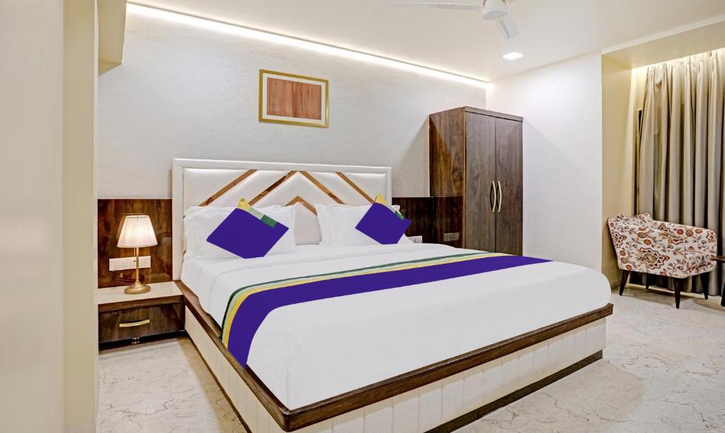 a bedroom with a large white bed and a chair at Treebo Tryst Golden Bliss Trimurti Nagar Square in Nagpur