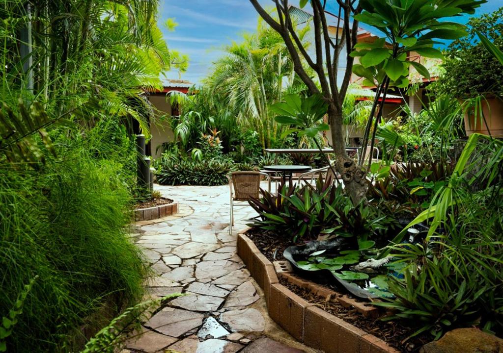 a garden with a patio with a table and plants at Kimberley Croc Motel in Kununurra