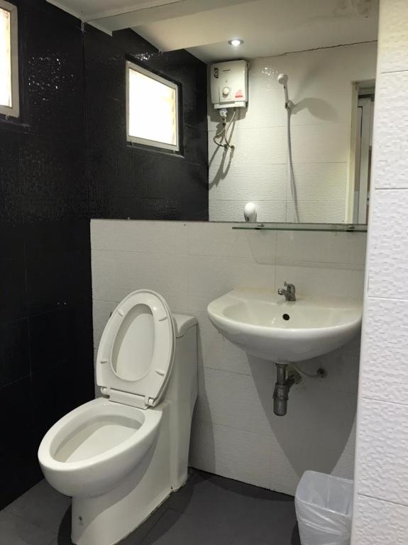 A compact bathroom with a wall-mounted sink, toilet and electric shower.