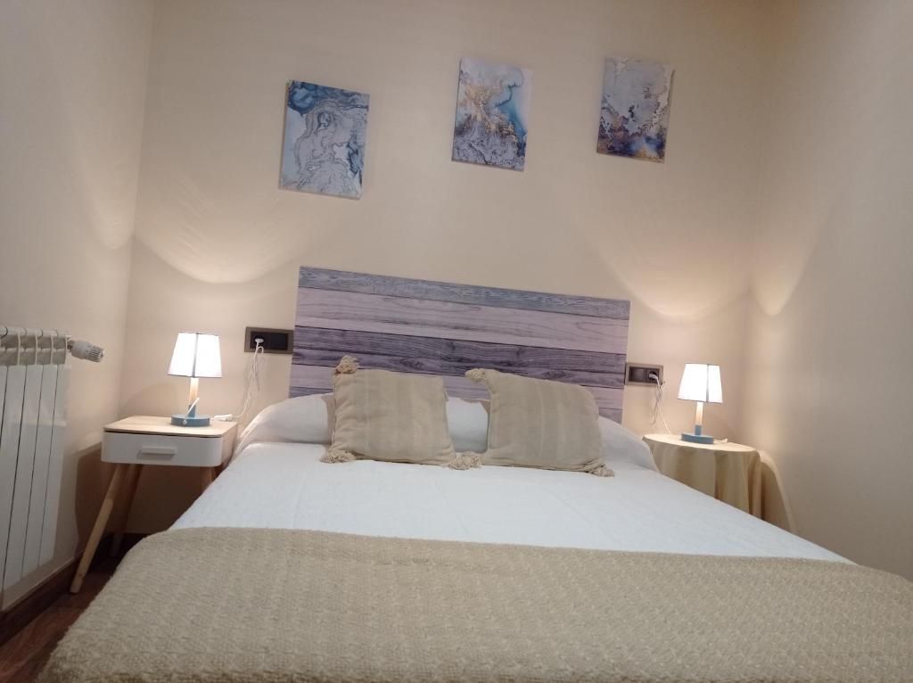 a bedroom with a large white bed with two lamps at Magia en el Arco in Olmedo