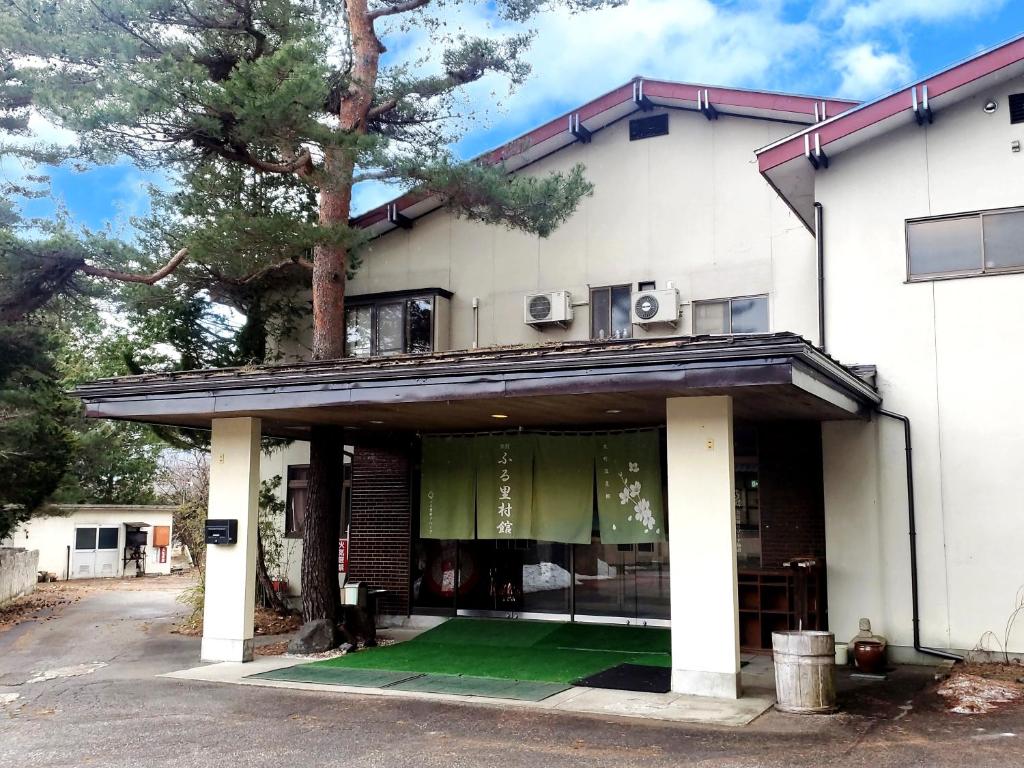 une maison avec une pelouse verte devant elle dans l'établissement Guest Room Furusatomura Kogeikan, à Omachi